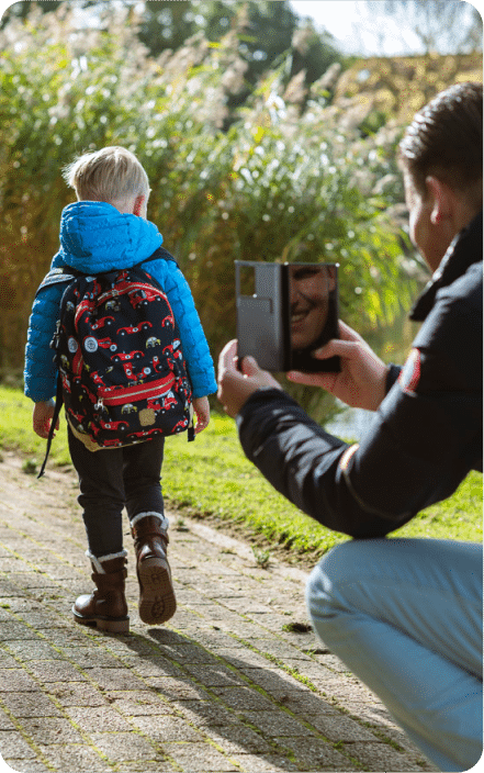 Un parent photographie son enfant avec son sac à dos